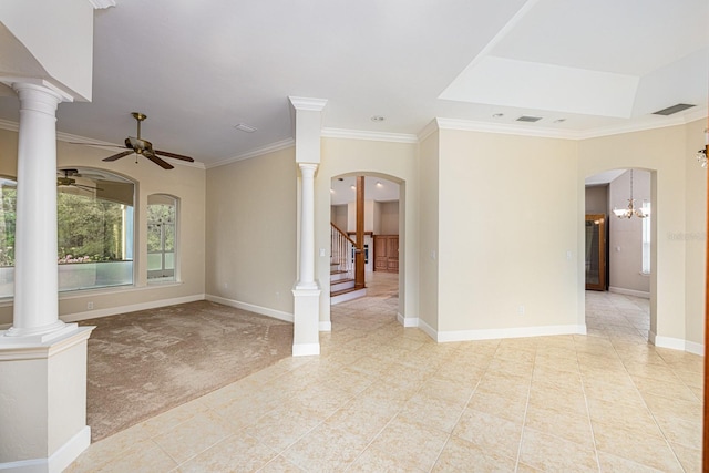 tiled empty room featuring decorative columns, ceiling fan with notable chandelier, a tray ceiling, and crown molding