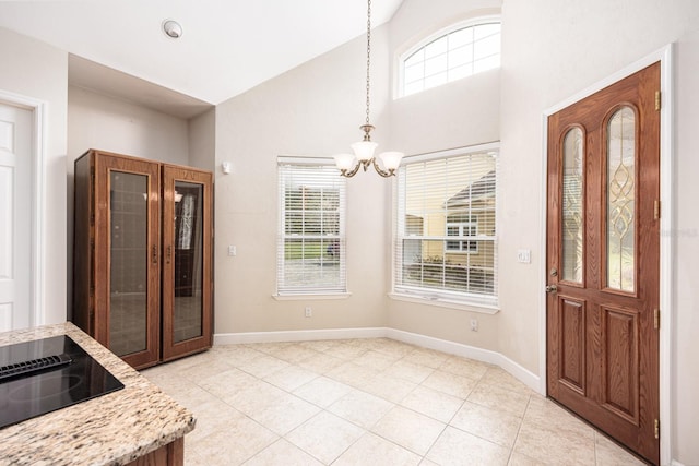 foyer with a healthy amount of sunlight, high vaulted ceiling, a notable chandelier, and light tile flooring