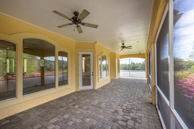 unfurnished sunroom featuring ceiling fan