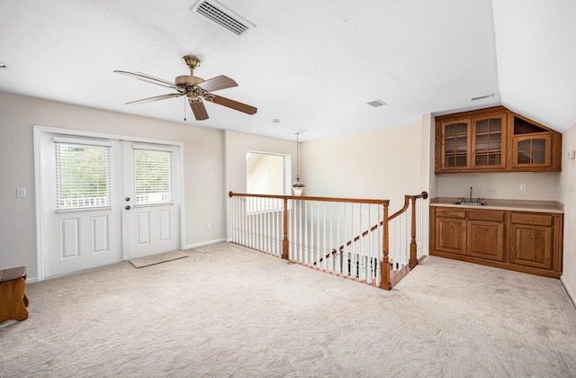 carpeted spare room with vaulted ceiling, ceiling fan, french doors, and sink