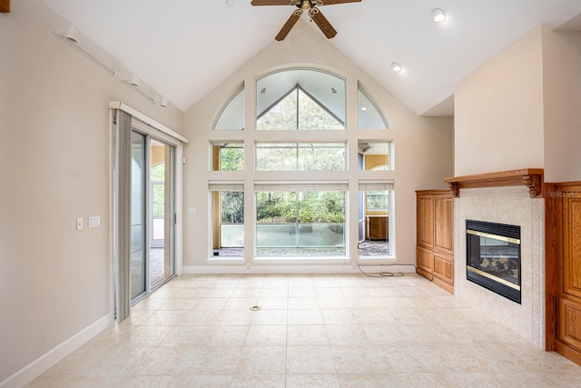 unfurnished living room featuring high vaulted ceiling, plenty of natural light, ceiling fan, and a tile fireplace