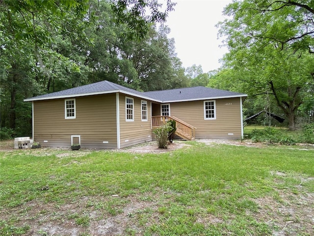 rear view of property featuring a wooden deck and a lawn