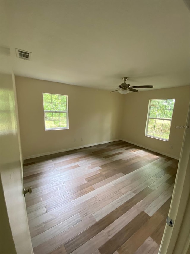 empty room with ceiling fan, light hardwood / wood-style flooring, and a healthy amount of sunlight