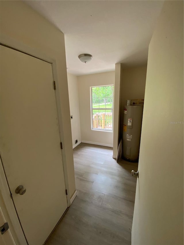 corridor featuring electric water heater and light hardwood / wood-style floors