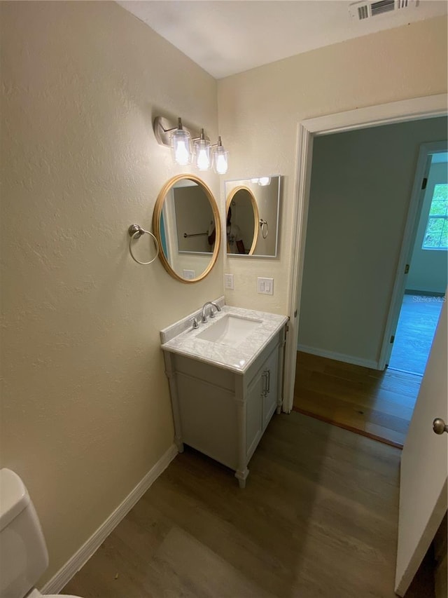 bathroom featuring vanity, hardwood / wood-style flooring, and toilet