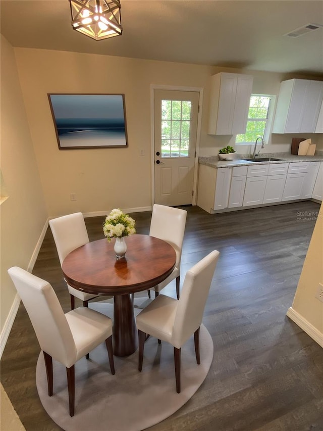 dining area featuring a notable chandelier, sink, and dark hardwood / wood-style flooring