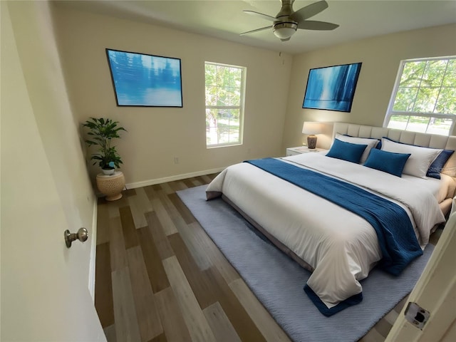 bedroom featuring multiple windows, hardwood / wood-style flooring, and ceiling fan