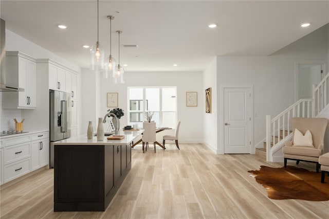 kitchen featuring decorative light fixtures, white cabinetry, an island with sink, and high quality fridge