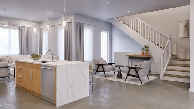 kitchen featuring stainless steel dishwasher, decorative light fixtures, sink, and an island with sink