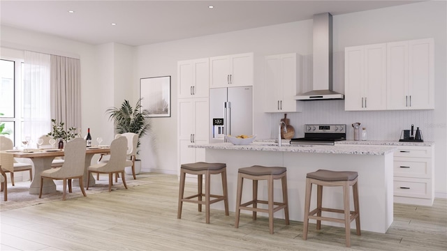 kitchen with white cabinets, wall chimney exhaust hood, stainless steel appliances, and a kitchen island with sink