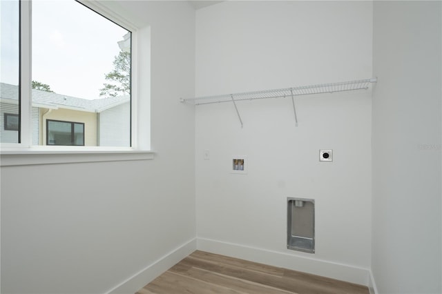 laundry area featuring electric dryer hookup, hookup for a washing machine, and light hardwood / wood-style flooring