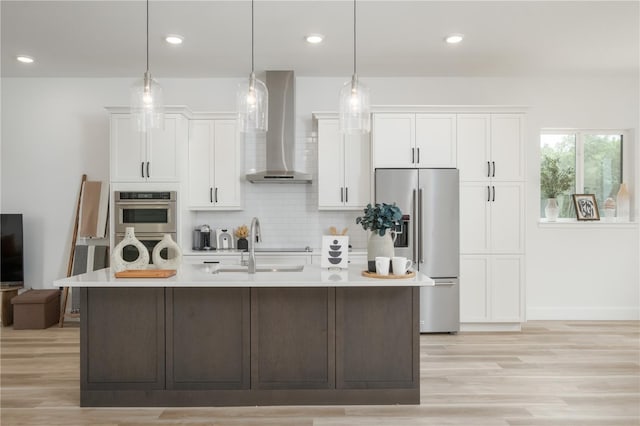 kitchen with white cabinetry, wall chimney range hood, hanging light fixtures, and appliances with stainless steel finishes