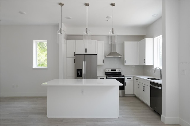 kitchen with wall chimney range hood, appliances with stainless steel finishes, a center island, and sink