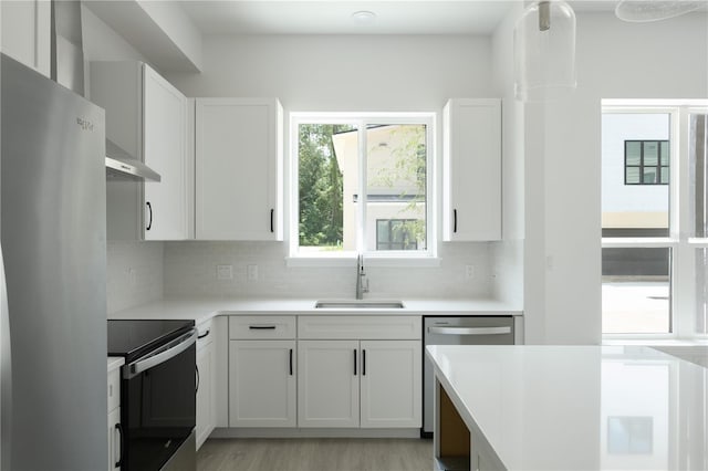 kitchen featuring sink, light wood-type flooring, tasteful backsplash, white cabinetry, and stainless steel appliances