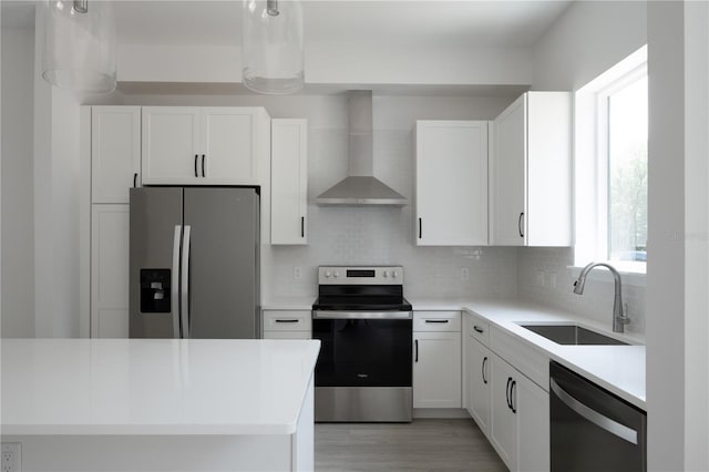 kitchen featuring white cabinetry, sink, wall chimney exhaust hood, stainless steel appliances, and light hardwood / wood-style flooring