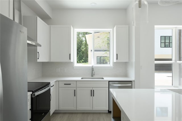 kitchen featuring backsplash, sink, light hardwood / wood-style floors, white cabinetry, and stainless steel appliances