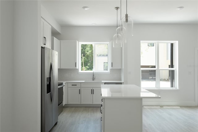 kitchen with tasteful backsplash, decorative light fixtures, a center island, appliances with stainless steel finishes, and white cabinets