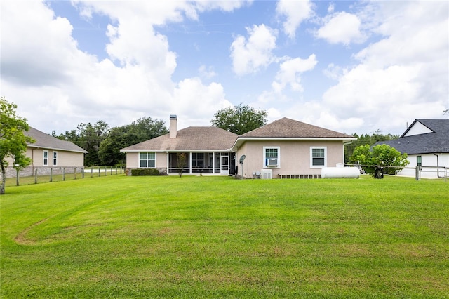 rear view of house with a lawn and a sunroom