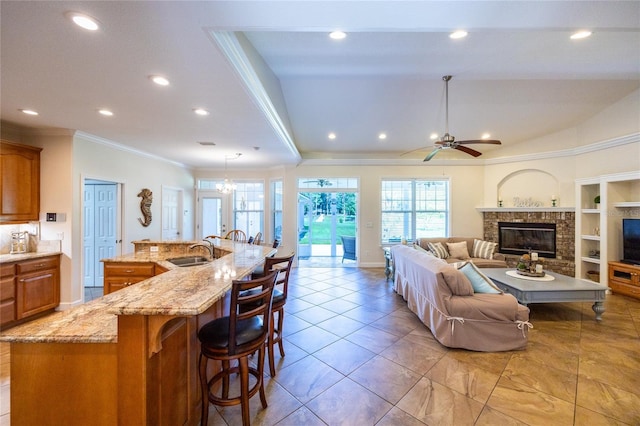 living room featuring ceiling fan with notable chandelier, crown molding, sink, and built in shelves