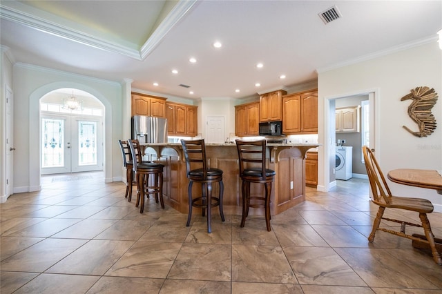 kitchen featuring a breakfast bar area, stainless steel fridge with ice dispenser, a center island with sink, and ornamental molding