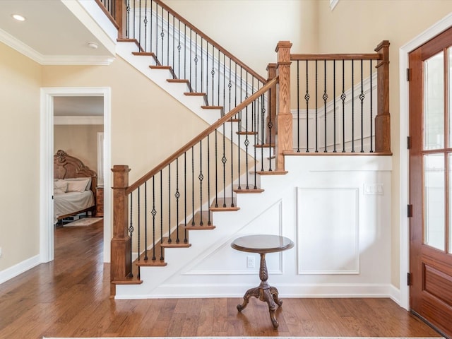 stairs with a wealth of natural light, dark hardwood / wood-style floors, and crown molding