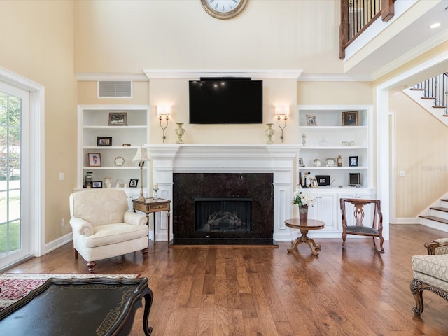 living room featuring a high end fireplace, dark hardwood / wood-style flooring, and a healthy amount of sunlight