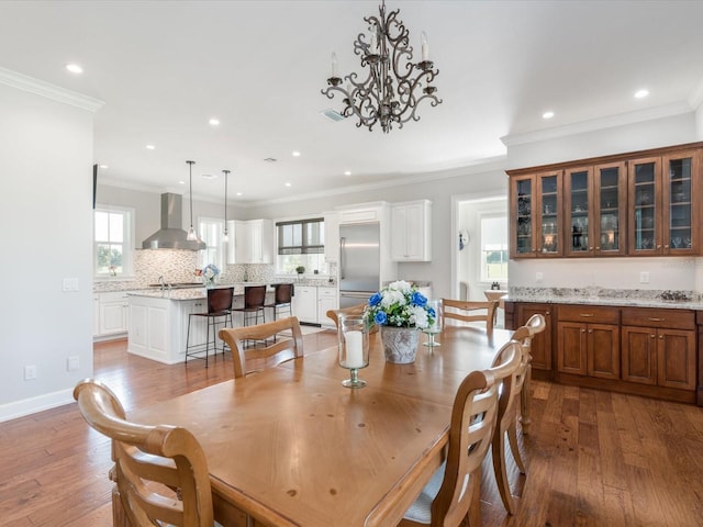 dining space with ornamental molding, a chandelier, and hardwood / wood-style flooring