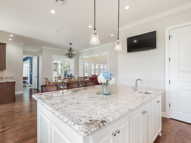 kitchen featuring pendant lighting, sink, a center island with sink, dark wood-type flooring, and white cabinetry