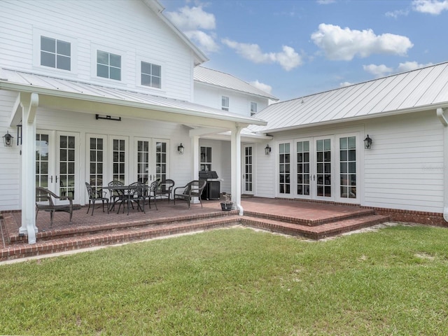 back of property featuring a yard, french doors, and a patio