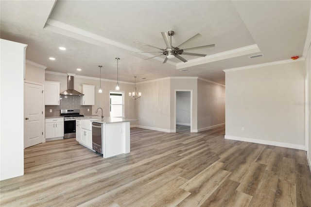 kitchen featuring white cabinetry, decorative light fixtures, a center island with sink, stainless steel appliances, and wall chimney range hood