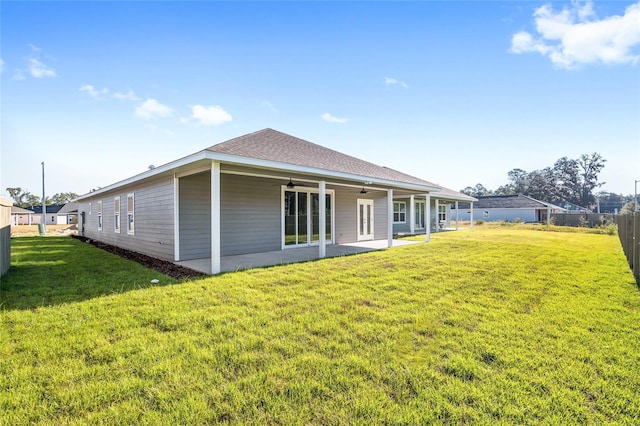 rear view of property featuring ceiling fan, a patio, and a lawn