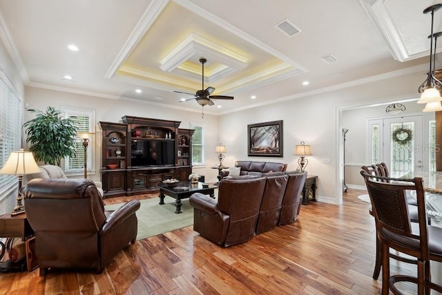 living room with a tray ceiling, hardwood / wood-style floors, ceiling fan, and crown molding