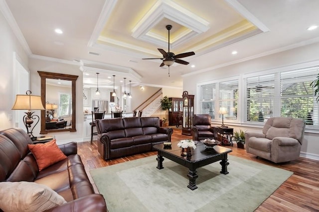 living room featuring hardwood / wood-style floors, ceiling fan, crown molding, and a tray ceiling