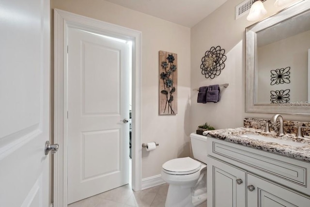 bathroom with toilet, vanity, and tile patterned flooring