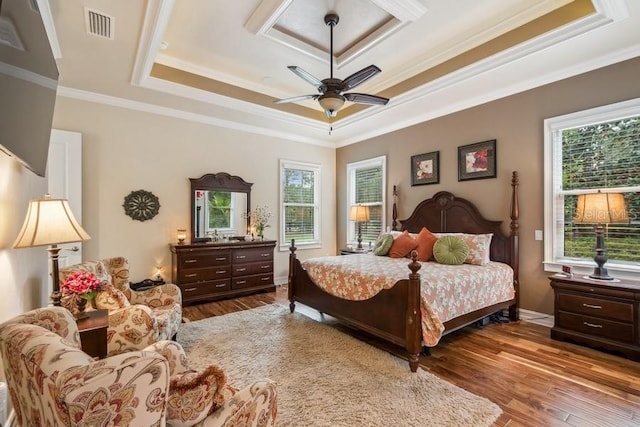 bedroom with light hardwood / wood-style floors, ceiling fan, crown molding, and a tray ceiling