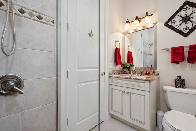 bathroom with toilet, vanity, and tiled shower