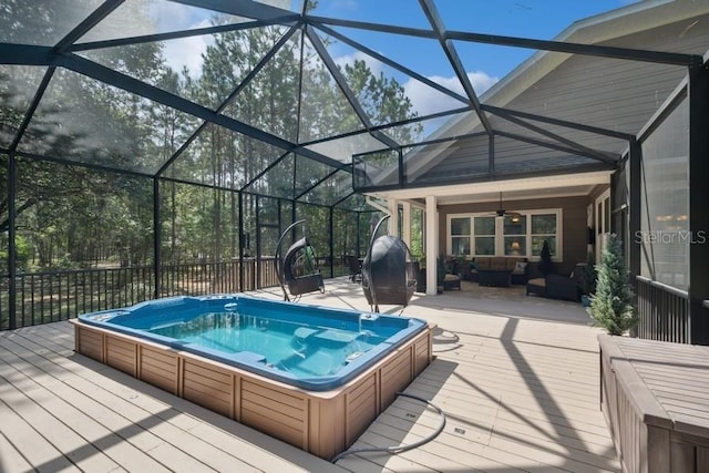 view of swimming pool with ceiling fan, a wooden deck, and glass enclosure