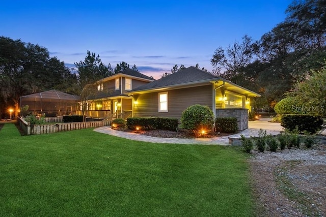 property exterior at dusk featuring a lawn and a lanai