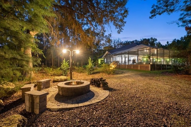 yard at dusk with a lanai and an outdoor fire pit