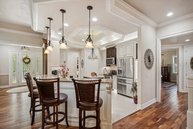 kitchen featuring light stone counters, appliances with stainless steel finishes, a breakfast bar area, decorative light fixtures, and dark hardwood / wood-style flooring