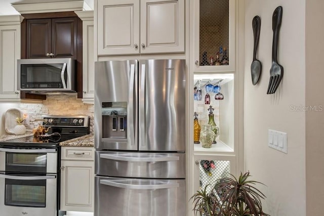 kitchen featuring decorative backsplash, appliances with stainless steel finishes, and light stone counters