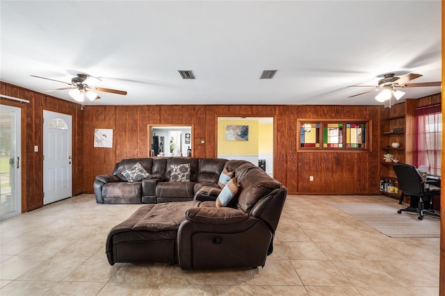 living room with wooden walls, ceiling fan, and a wealth of natural light