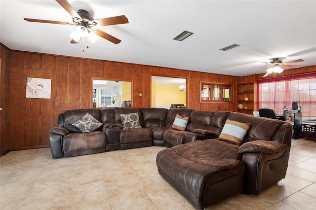 living room featuring wooden walls, ceiling fan, and light tile patterned flooring