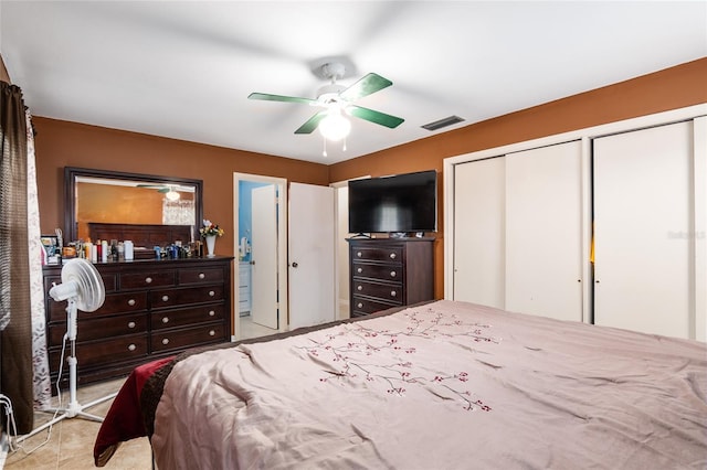 bedroom featuring ceiling fan, ensuite bathroom, and multiple closets