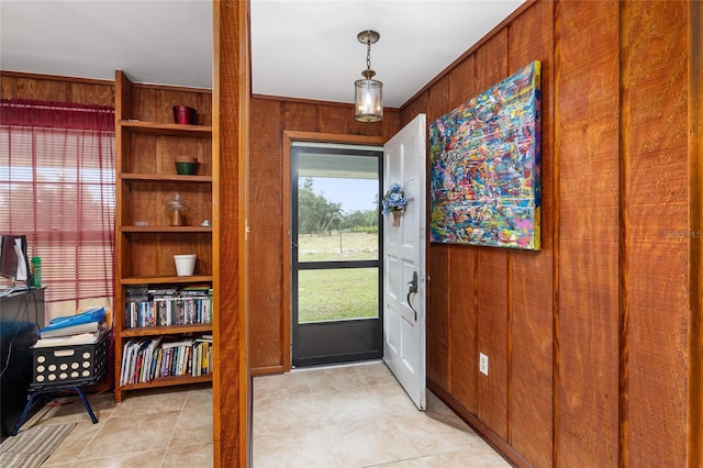 entrance foyer featuring light tile patterned floors, wooden walls, and ornamental molding