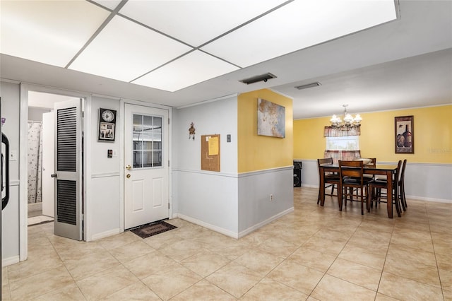 foyer with light tile patterned flooring and an inviting chandelier