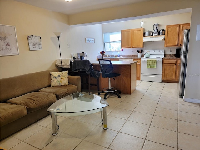 kitchen featuring a kitchen bar, light tile patterned floors, sink, a kitchen island, and electric range