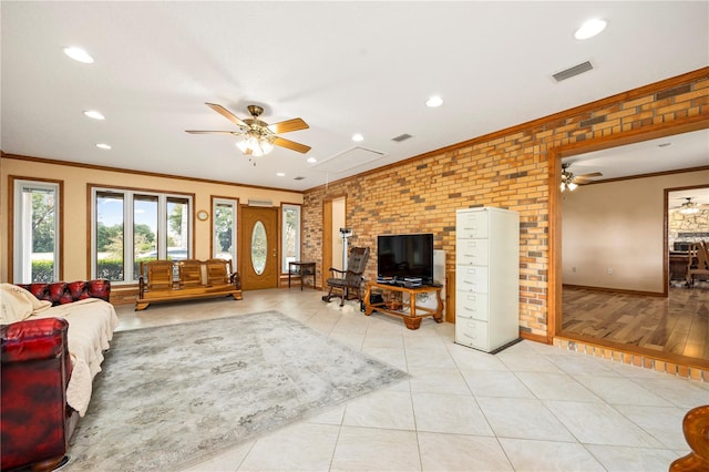 living room featuring brick wall, ornamental molding, light hardwood / wood-style floors, and ceiling fan