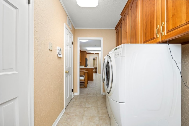 washroom with cabinets, washer / dryer, light tile floors, a textured ceiling, and ornamental molding