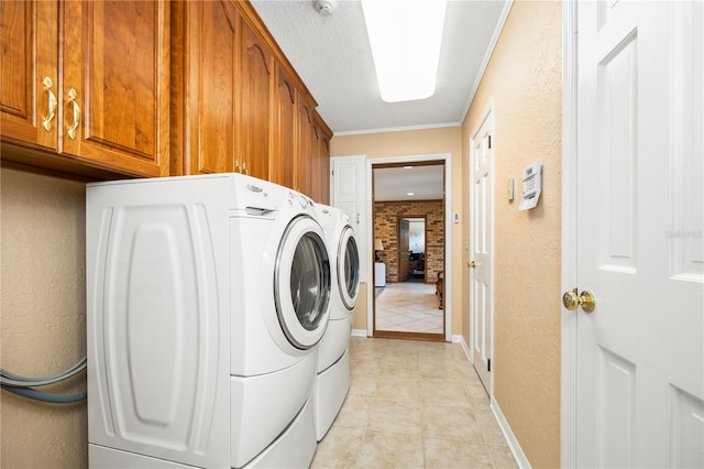 laundry room featuring brick wall, light tile flooring, washing machine and clothes dryer, cabinets, and crown molding